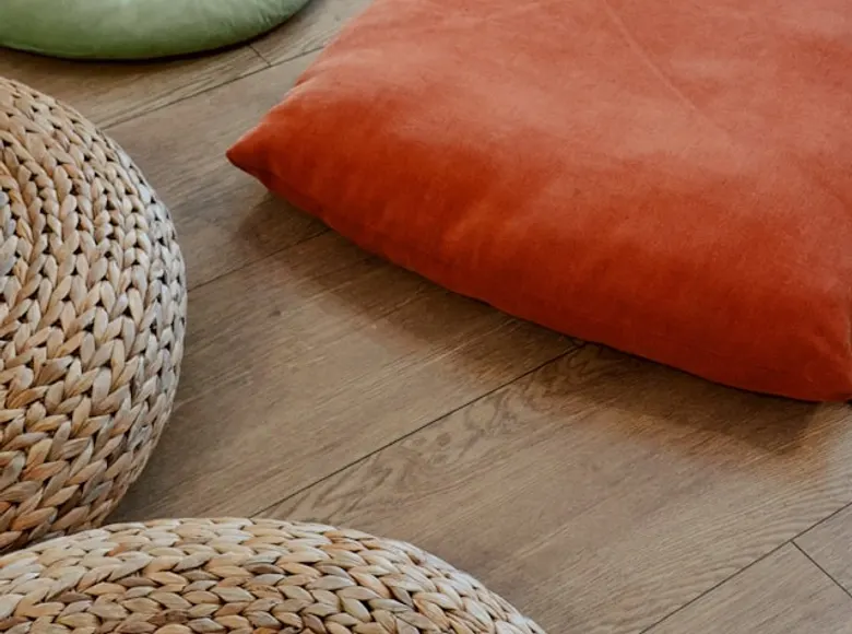 Round woven floor cushions arranged on a warm wooden floor