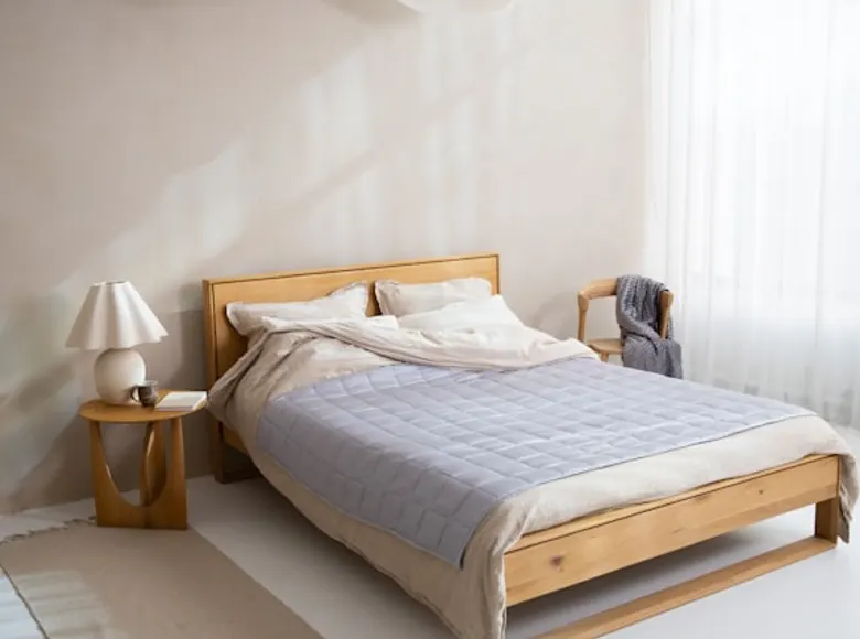 A made bed with layered neutral linens and a bedside lamp